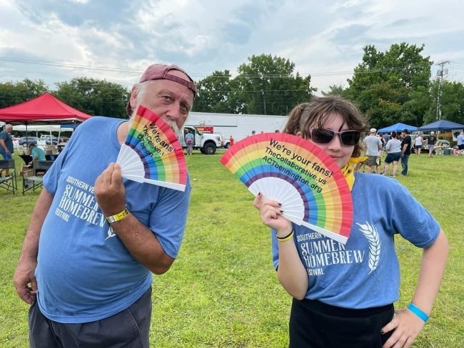 Two community members at the Brew Fest event holding rainbow fans
