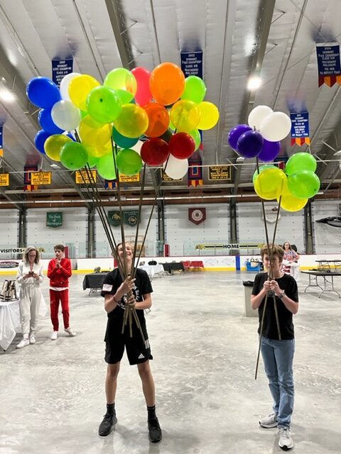 BalloonsRTUPageWebsiteRevision Two high school boys holding clutches of colorful helium balloons